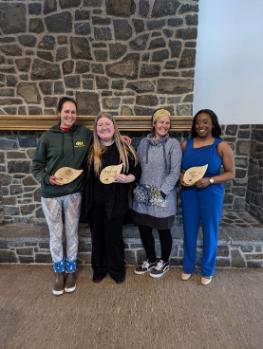 Four students standing with incubator plaques